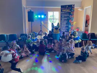 Bluey character joining smiling children at a Nellie B's traditional party