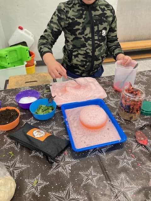 Children watching a colourful science experiment fizz and foam